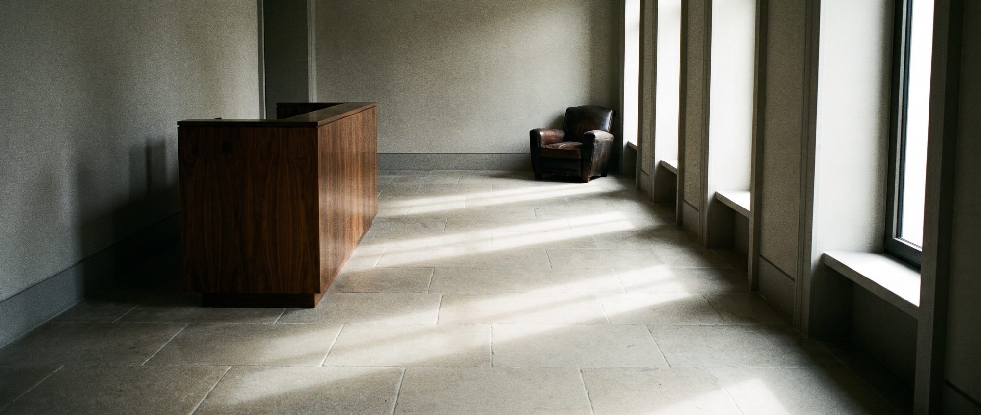 The stone entrance hall of a private office building in long light