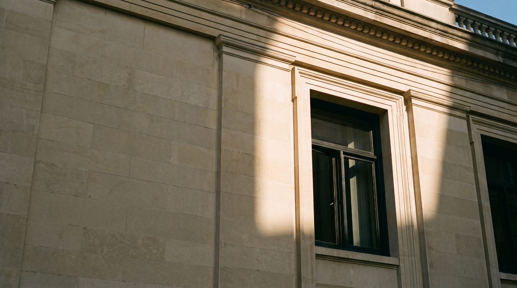 Raking afternoon light across the stone cornice of a classical bank building